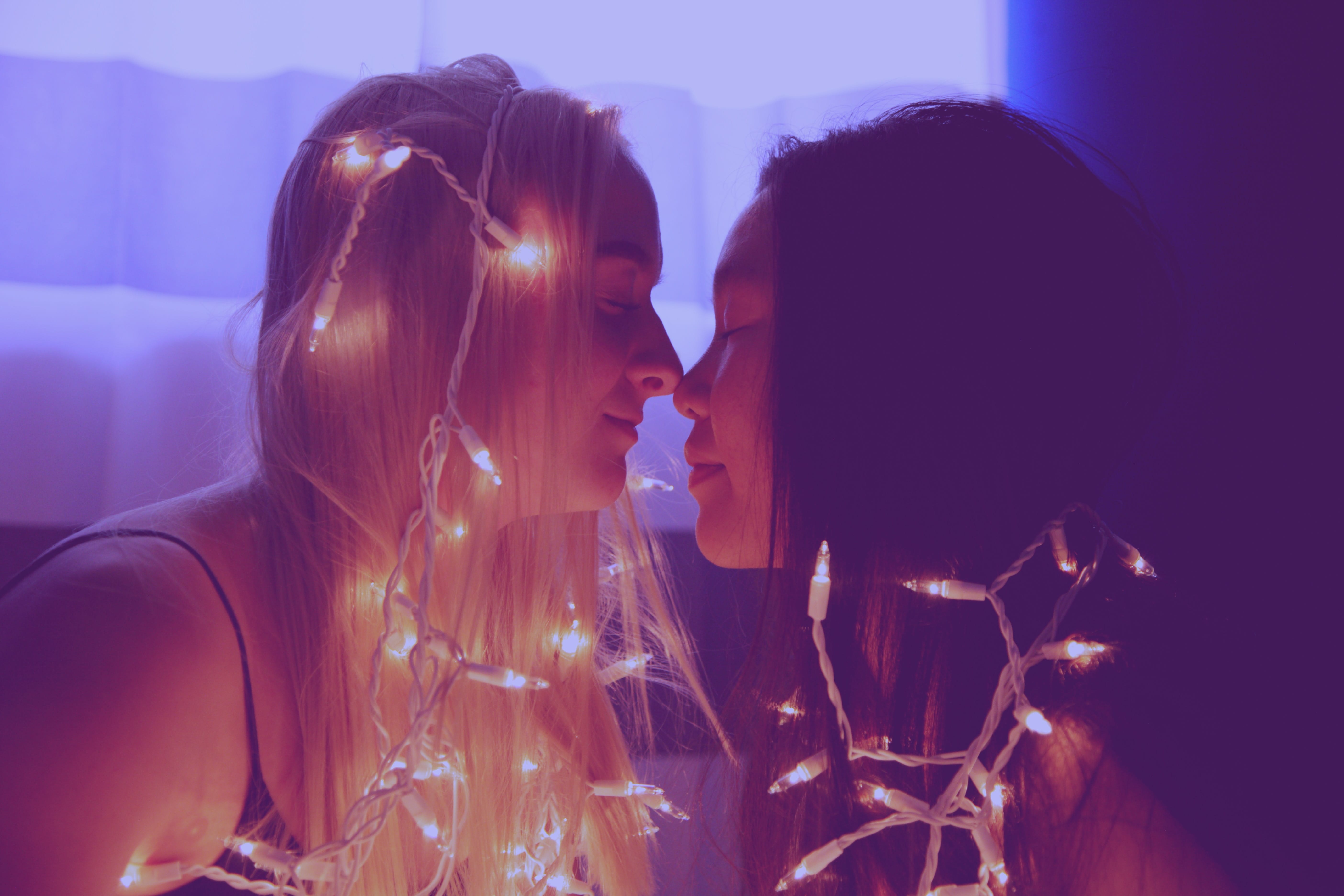 Girls touching noses in christmas lights