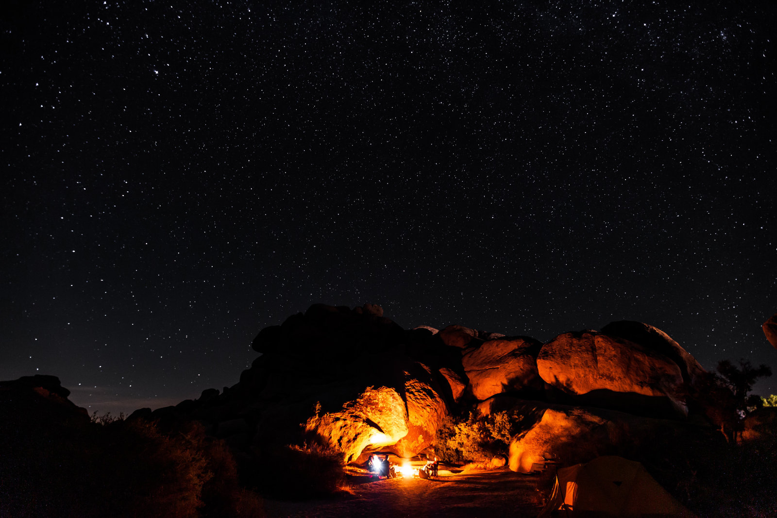 A campfire illuminates a nighttime desert landscape.