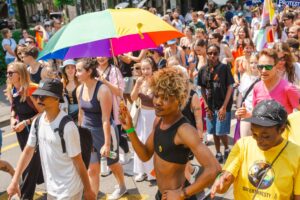 A diverse group of people march in solidarity at a Pride parade.