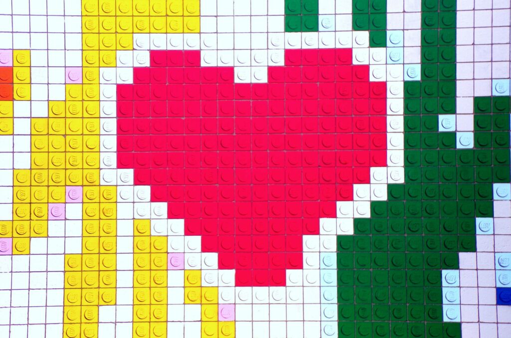 A lego puzzle with hands reaching across a pink heart