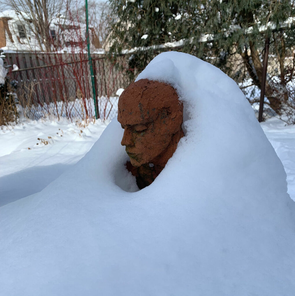 A red stone statuary in a snow covered yard